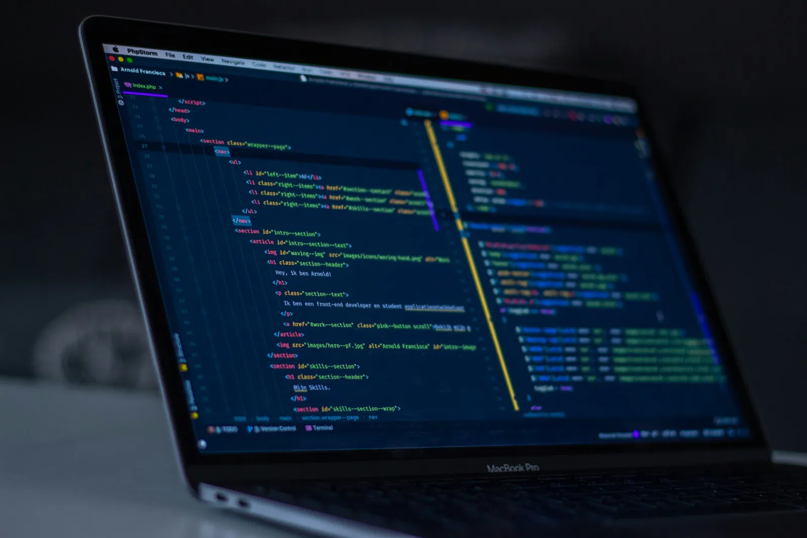 A laptop on a dark desk showing a code editor.