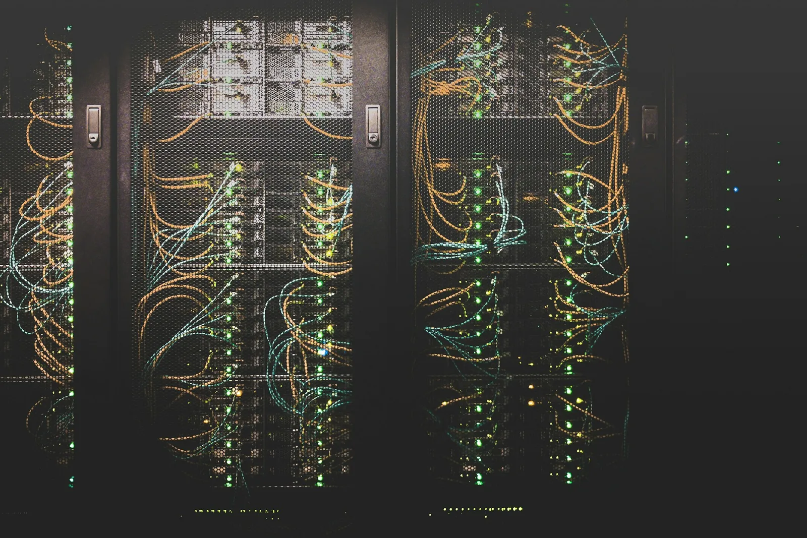 Rows of server racks with neatly bundled cabling in a dark data centre.